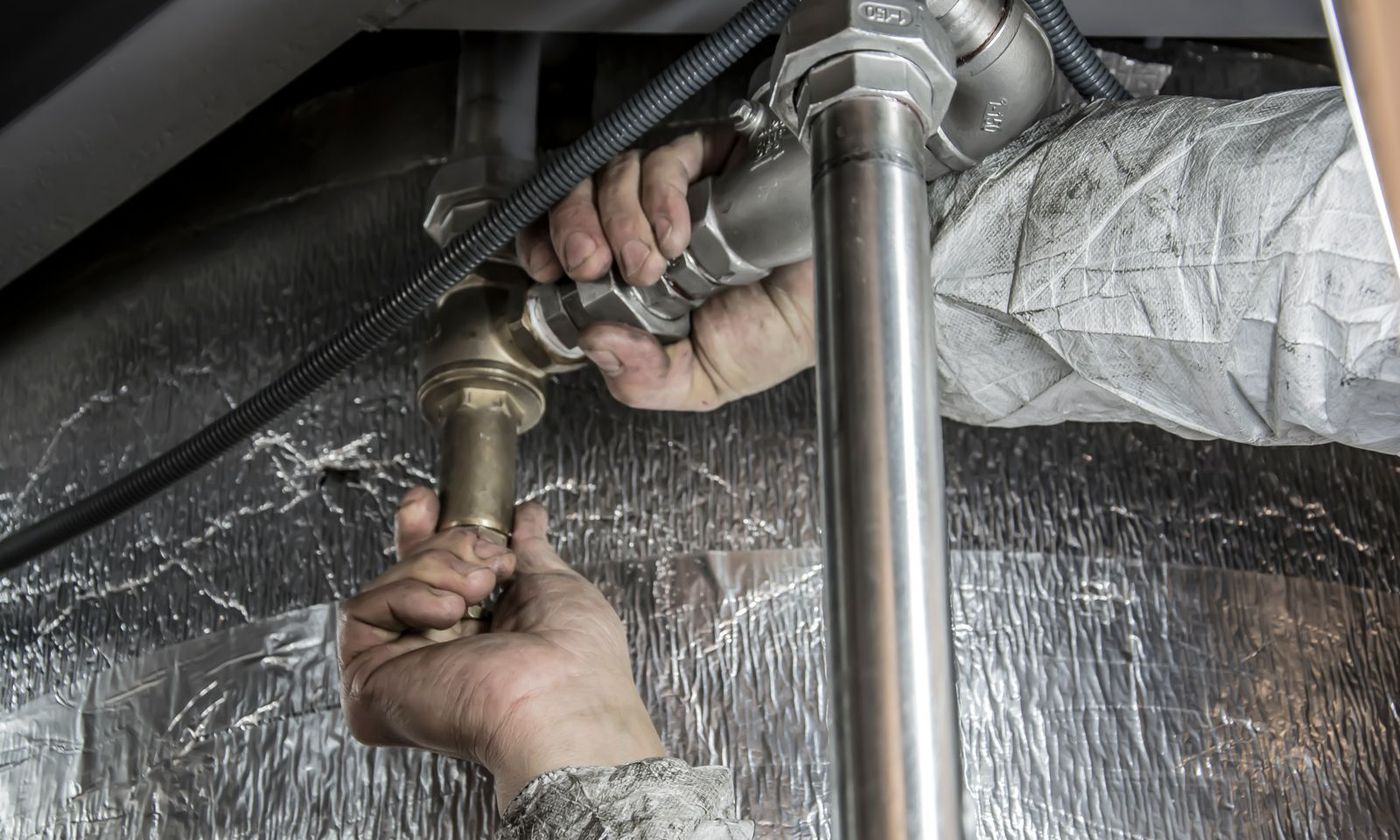Plumber tightening a threaded pipe connection to stop a leak
